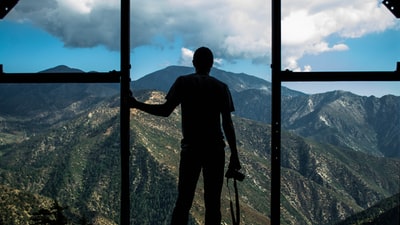 白天站在门附近俯瞰山的人的剪影照片